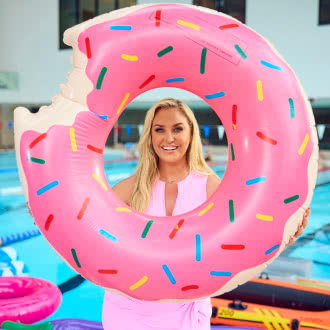 TV celebrity Josie Gibson by a swimming pool holding a giant inflatable donut