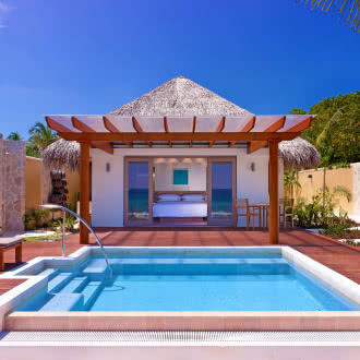 a luxury hotel room with a swimming pool, sunloungers and a covered terrace